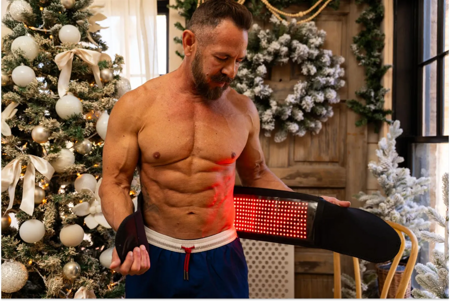 Fit man using a MitoRedLight red light therapy wrap on his core for post-workout muscle soreness recovery.