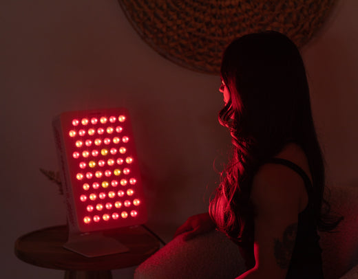 woman sitting in front of red light therapy device at home