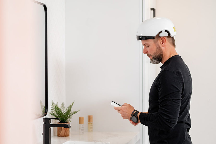 man on his phone while using Mito hair helmet and hair mist.