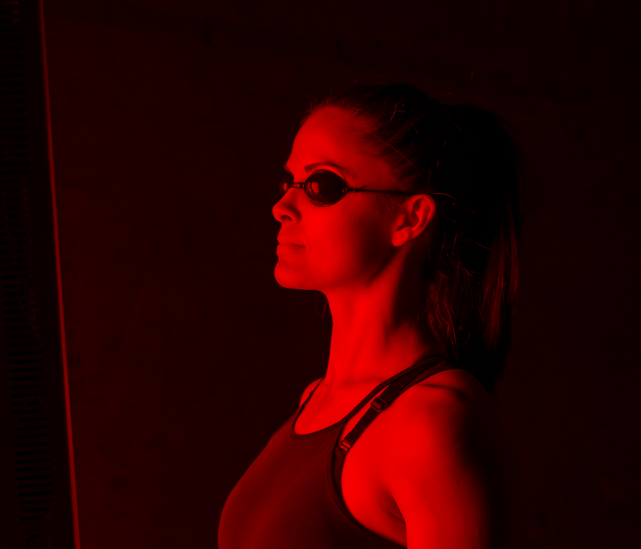 Woman in front of red light panel to increase her collagen production.