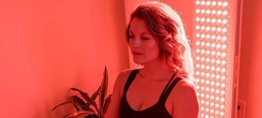 woman sitting in front of red light therapy panel at home