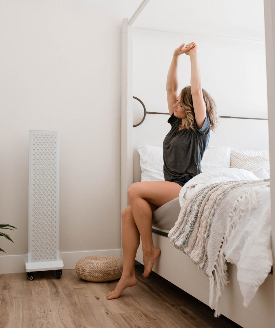 man sitting on the side of the bed stretching.