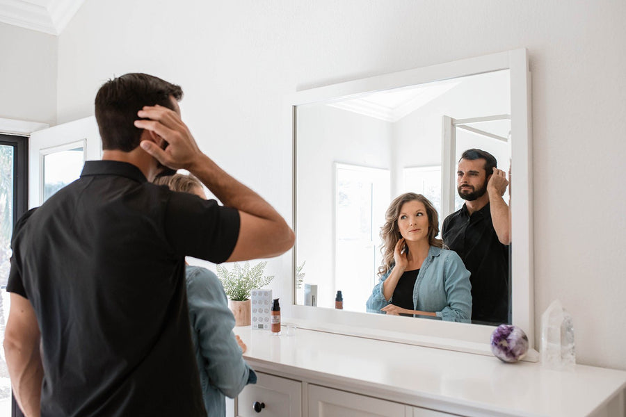 Person examining hair in mirror - red light therapy for hair growth