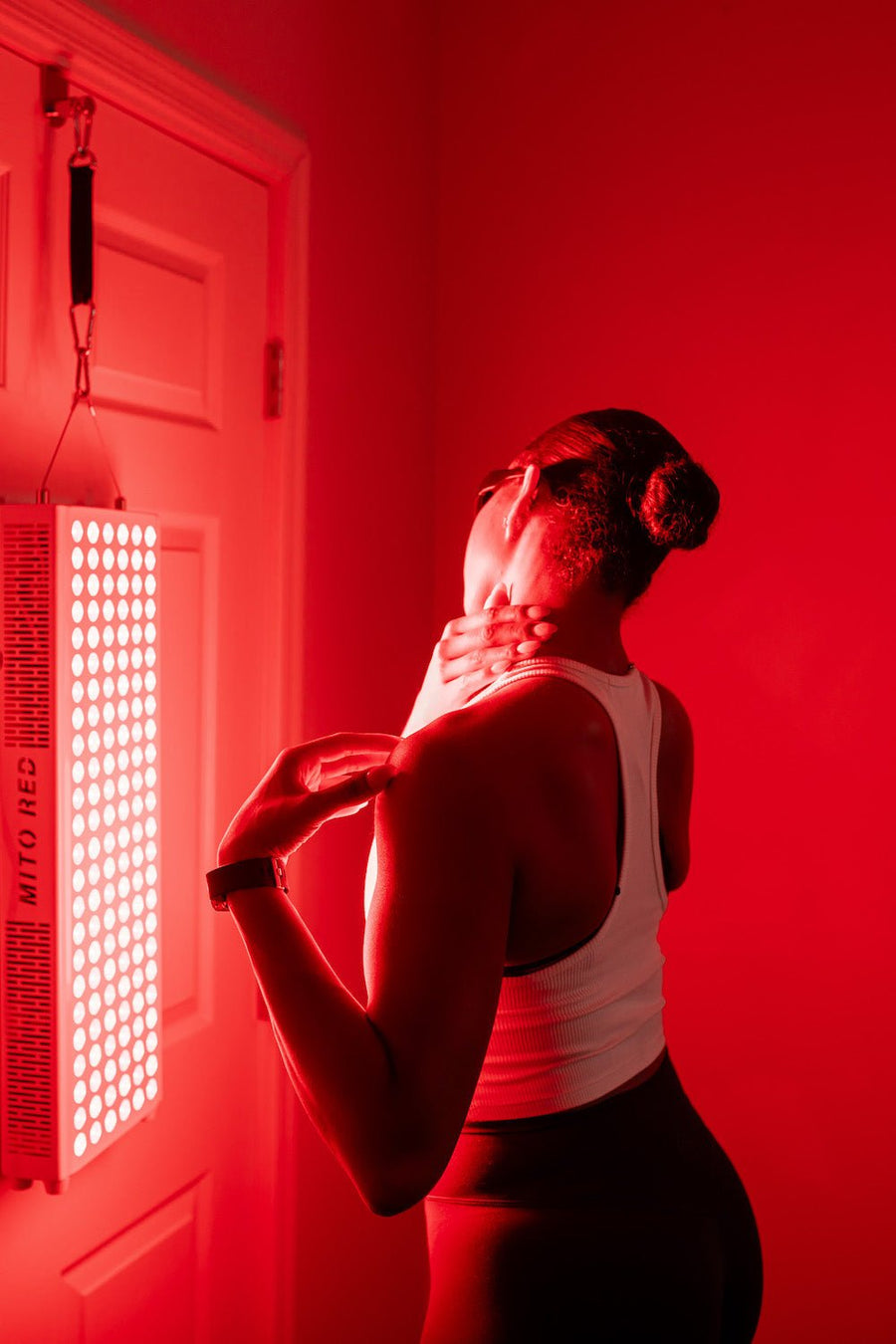 woman standing in front of red light panel to help get rid of cellulite.