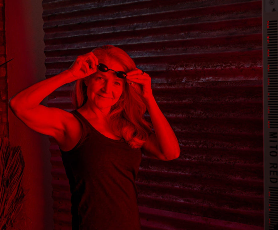 middle aged woman putting on safety glasses.in front of red light therapy device