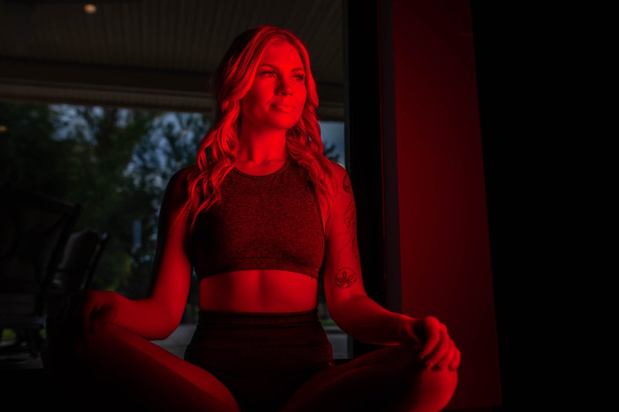 woman sitting in front of red light panel to help with weight loss.