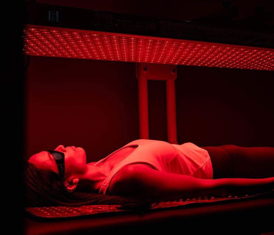 woman laying down inside of commercial red light therapy bed.