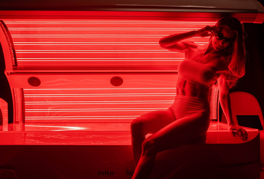 woman sitting on the side of red light therapy bed.