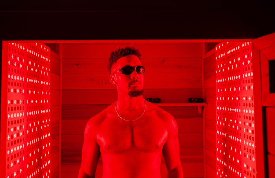 man standing inside of red light therapy room with panels on either side to absorb the best wavelengths.