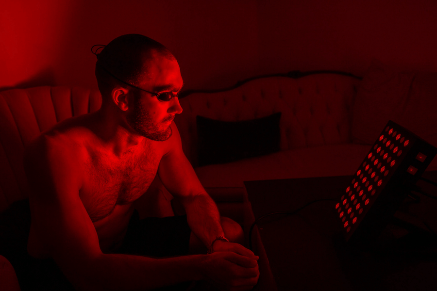 Man sitting in front of red light panel for skin therapy