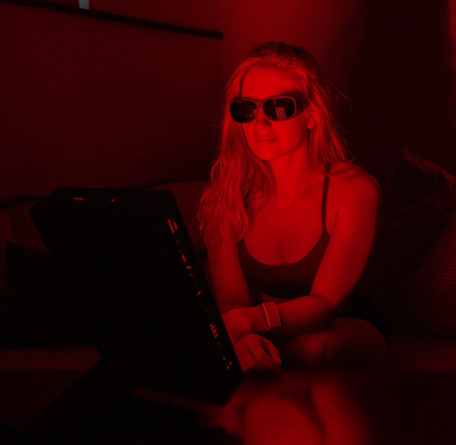 woman sitting in front of red light panel to help with skin health.