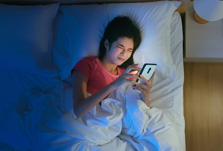 woman looking at her phone while laying in bed.