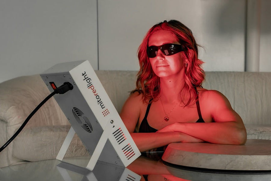 Woman sitting in front of Mito Red Light Therapy panel for skin rejuvenation session.