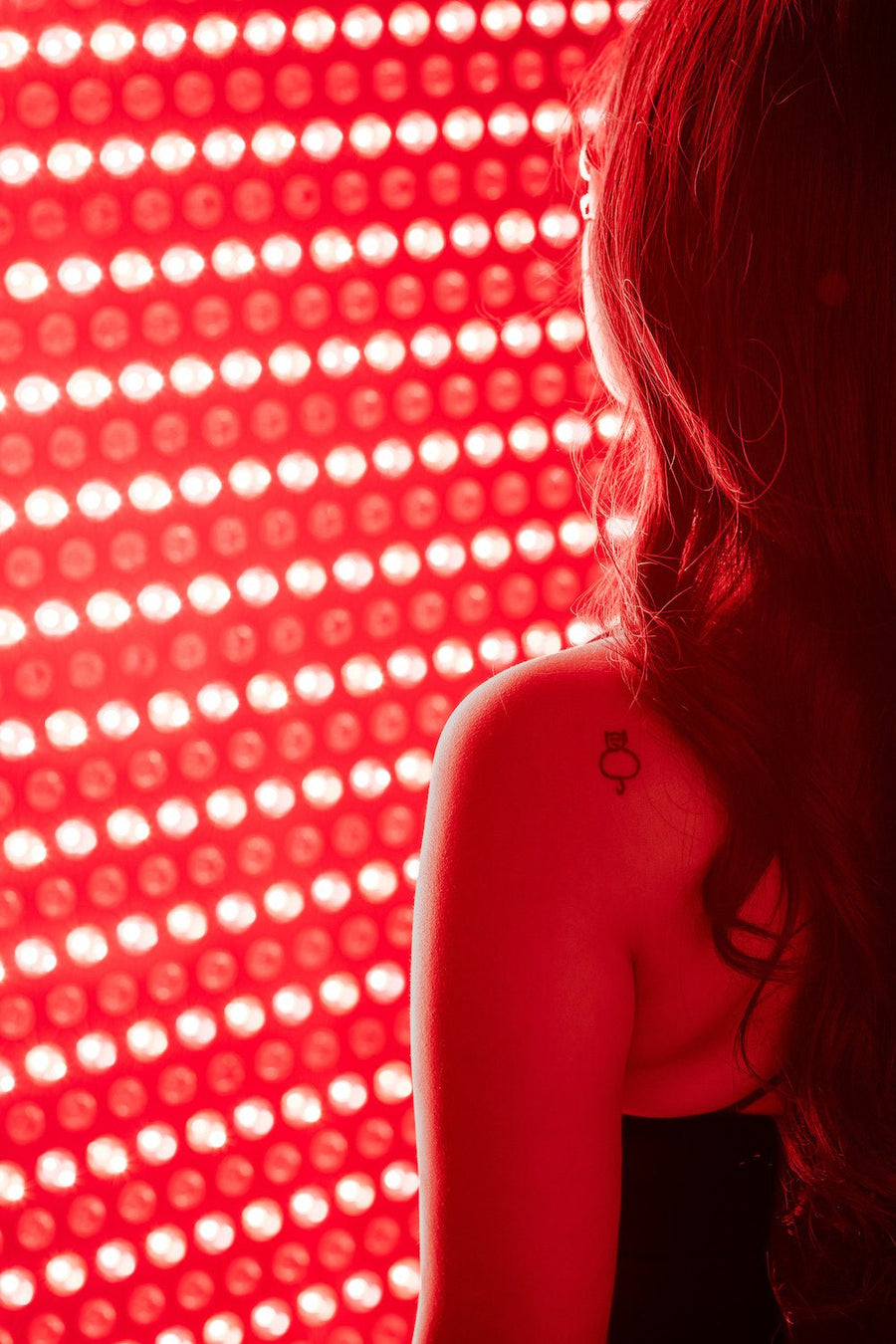 woman standing in front of red light panel for red light and near infrared light therapy.